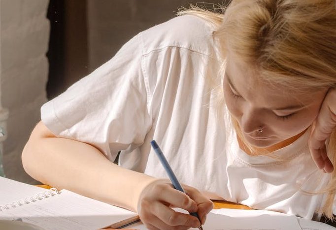 woman in white shirt writing on white paper