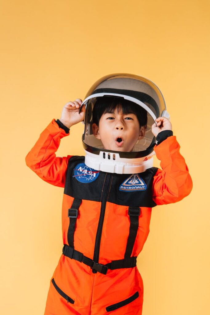 expressive asian boy putting on spaceman helmet